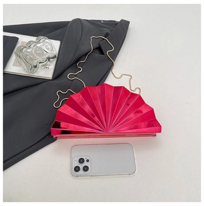 Macro detail of glossy magenta fan-shaped evening bag with a delicate gold chain strap