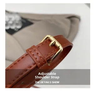 Detail of adjustable brown leather shoulder strap with elegant gold metal buckle