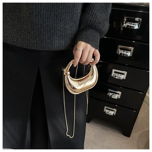 Macro detail of crescent-shaped acrylic clutch showing high-gloss golden mirror finish