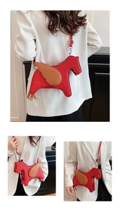 Detail view of red leather pegasus bag with brown wing accents and adjustable strap