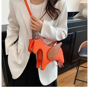 Detail of creative orange Pegasus crossbody bag with brown wings and textured finish