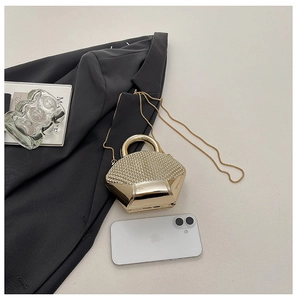 Detail of golden shell-shaped evening clutch bag with woven texture and metal mirror finish