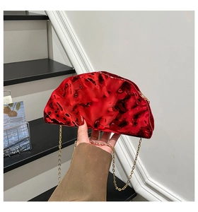 Macro view of metallic red wrinkled evening clutch bag with gold chain strap detail