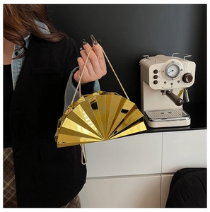 Macro view of gold fan-shaped clutch bag with polished metallic mirror finish and chain