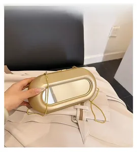 Detail of a gold capsule evening bag with a mirror finish and fine chain strap