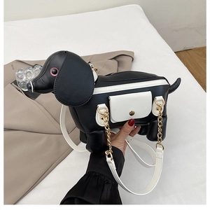 Détail du sac chiot noir et blanc avec chaîne dorée et bandoulière blanche élégante