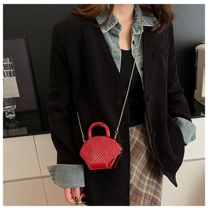 Close-up of a mini red acrylic crossbody bag with quilted metallic finish on a model