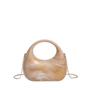 Detail of amber texture acrylic handbag with golden chain and circular handle