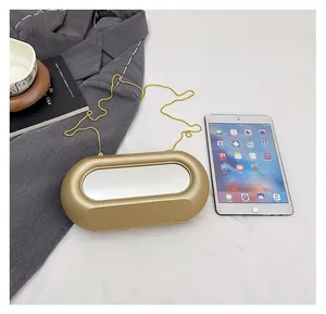 Macro shot of gold acrylic evening clutch bag showing size ratio with iPad and suit