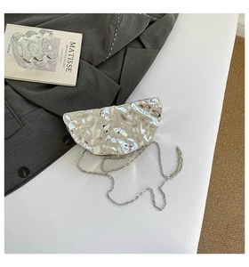 Macro view of silver half-moon evening bag with metallic ice-crack texture and chain