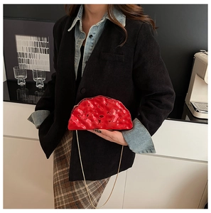 Dettaglio borsa a nuvola rossa metallizzata con catena dorata indossata da modella