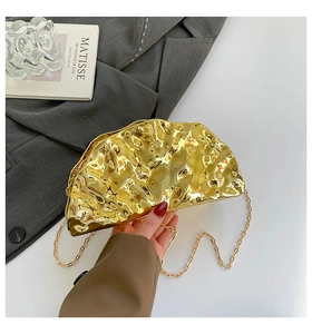Close-up of golden metallic pleated shell evening bag with elegant metal chain strap