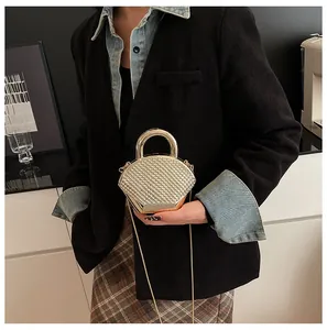 Detail of champagne gold evening bag with geometric woven texture and metal ring handle