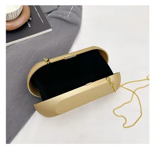 Interior detail of golden oval metal clutch bag showing black velvet lining and chain