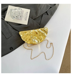 Detailed view of semi-circular gold clutch bag with crinkled metallic texture and chain