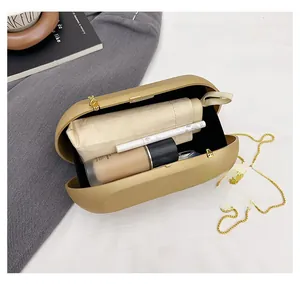 Macro view of gold acrylic box bag showing interior capacity with cosmetics and chain strap