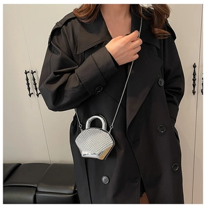 Silver rhinestone mini clutch bag worn on a black trench coat with a sleek chain strap