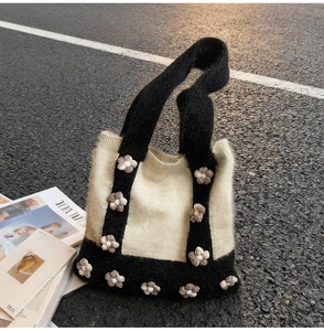 Detail of soft black and white knit tote bag with 3D floral accents and fuzzy texture