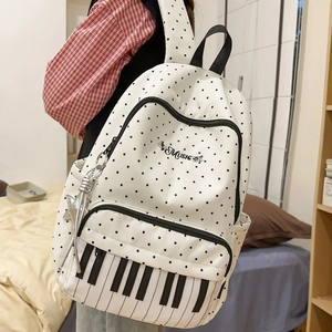 Student backpack with piano key design and polka dots on a girl in a red plaid shirt