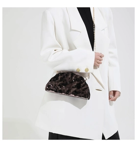 Brown acrylic shell bag with ice crack texture and gold chain on a white blazer