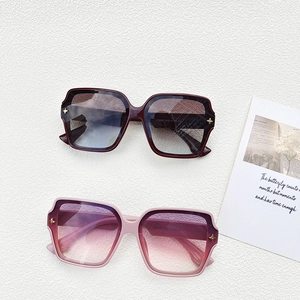 Détail de lunettes de soleil carrées oversize avec verres dégradés et rivets étoile dorés