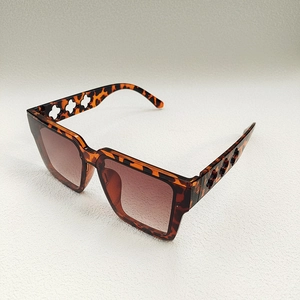 Detail of tortoise shell sunglasses with clover cutout on temples and brown gradient lenses