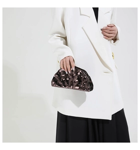 Detail showing wavy liquid metal texture on a bronze shell-shaped acrylic clutch bag