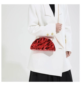 Detail of red acrylic evening bag featuring fluid 3D wave texture and golden chain