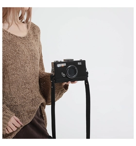 Detail of retro camera shaped crossbody bag featuring 3D lens design and wide fabric strap