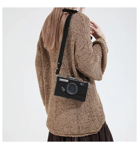 Detailed view of the black retro camera-shaped crossbody bag worn by a model