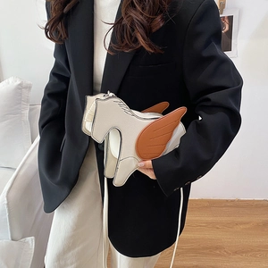 Creative white Pegasus crossbody bag in litchi leather worn over a black blazer