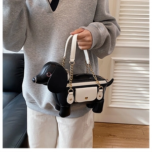 Detail of dachshund puppy shaped shoulder bag featuring white handles and gold metal chain