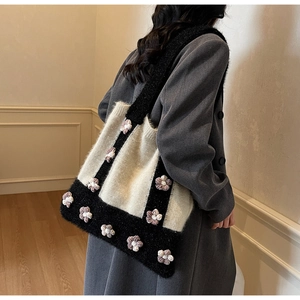 Detail of a knit tote bag with black and white contrast and 3D crochet flowers