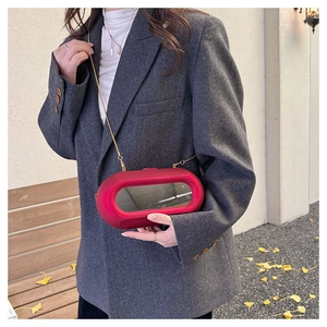 Detail of red capsule clutch bag with a transparent window and gold chain strap