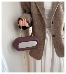Detail view of purple oval acrylic bag with silver mirror panel and gold chain strap