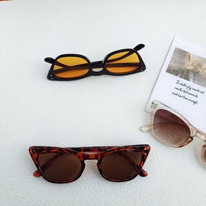 Three retro cat-eye sunglasses with metal rivets on textured white surface with card