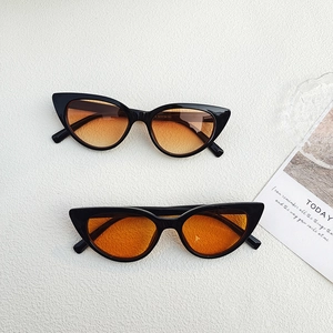 Retro cat-eye sunglasses with black frames and orange gradient lenses on white backdrop