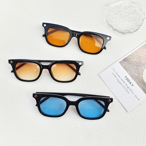 Occhiali da sole quadrati vintage in arancione, giallo e blu su sfondo bianco testurizzato