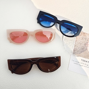 Lunettes de soleil œil de chat vintage en noir, rose et marron sur fond blanc texturé