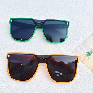 Oversized one-piece sunglasses in green and orange frames with dark tinted lenses