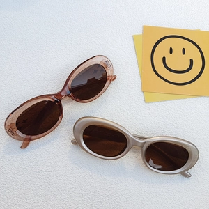 Détail de lunettes de soleil ovales rétro en couleurs marron gelée et doré champagne