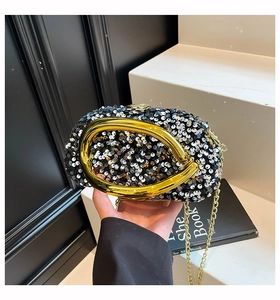 Detail of evening clutch featuring black silver sequins and a large gold U-shaped handle