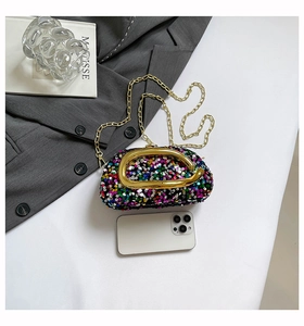 Detailed view of sequin evening bag with gold horseshoe buckle and chain for size reference