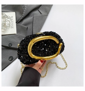 Detail of black sequined evening bag with gold C-handle and chain strap for women