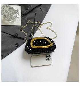Macro detail of black sequin evening clutch with chunky gold metal handle and chain