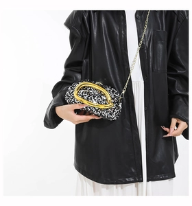 Detail of sequined evening clutch with gold semi-circle handle and crossbody chain strap