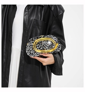 Detail of glitter evening bag with black sequins and a gold horseshoe metal handle