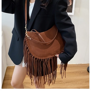 Detail of brown suede crescent bag with bohemian long tassels and adjustable strap