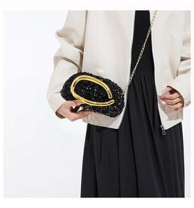 Macro detail of black sequin evening bag with elegant gold metal curved handle and chain