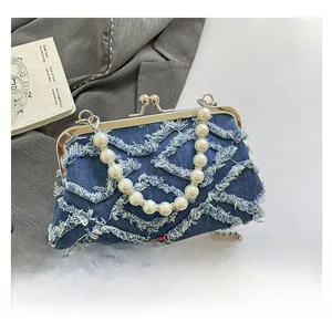 Close-up of blue denim shell bag with diamond fringe quilting and pearl handle